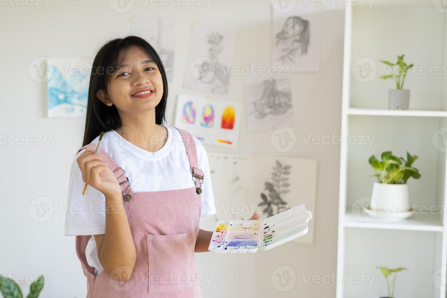 Young girl standing on the floor and hold Color palette and brush at room. Hobby and art study at home. photo