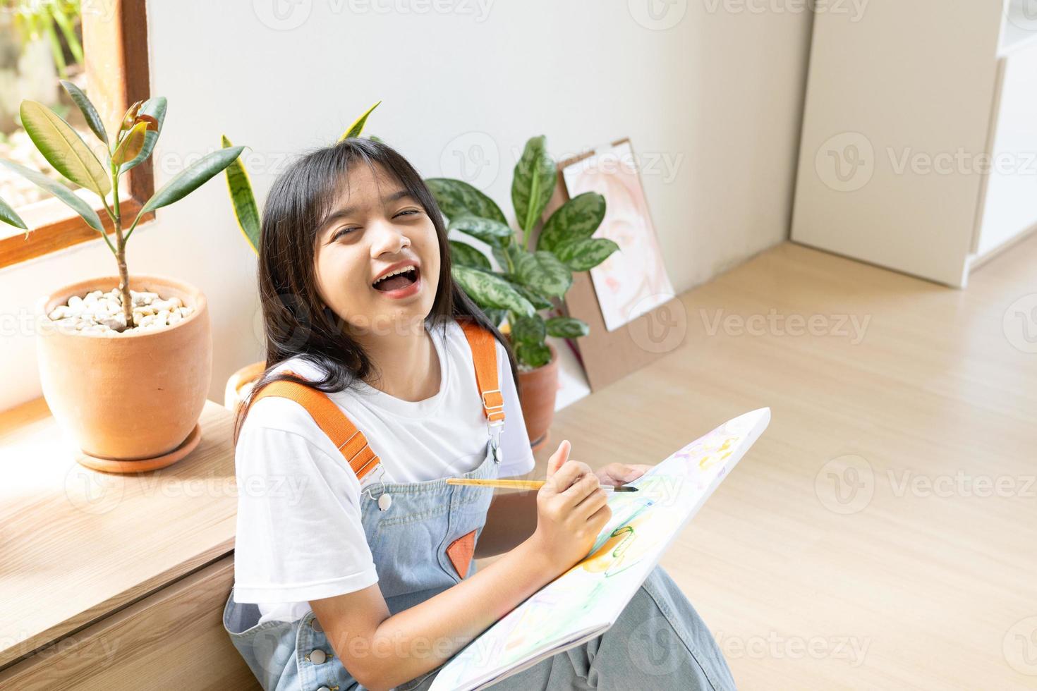 niña sentada en el suelo y pintando sobre papel en casa. hobby y estudio de arte en casa. foto