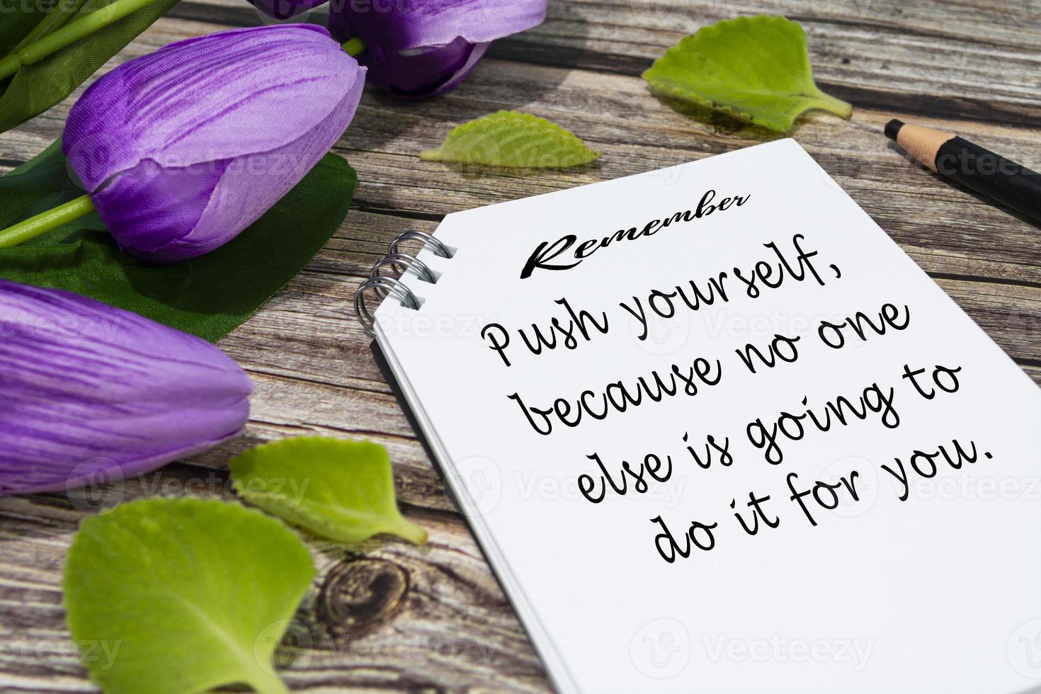 Motivational quote on notepad with flowers on wooden desk. photo