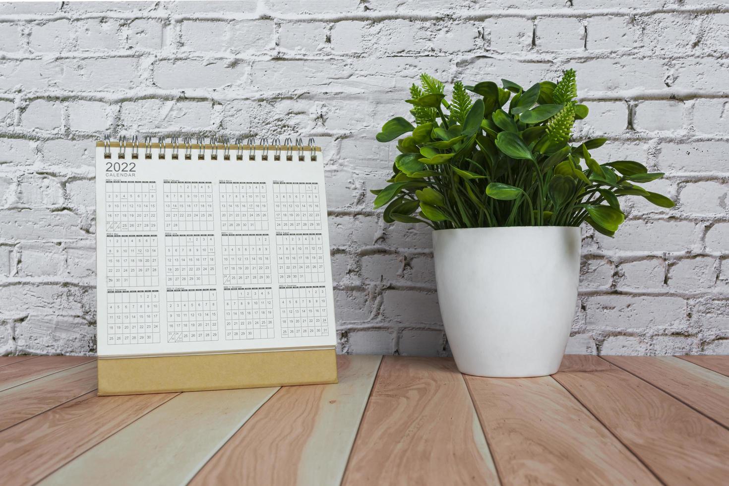 2022 calendar with potted plant on wooden desk. New year concept. photo