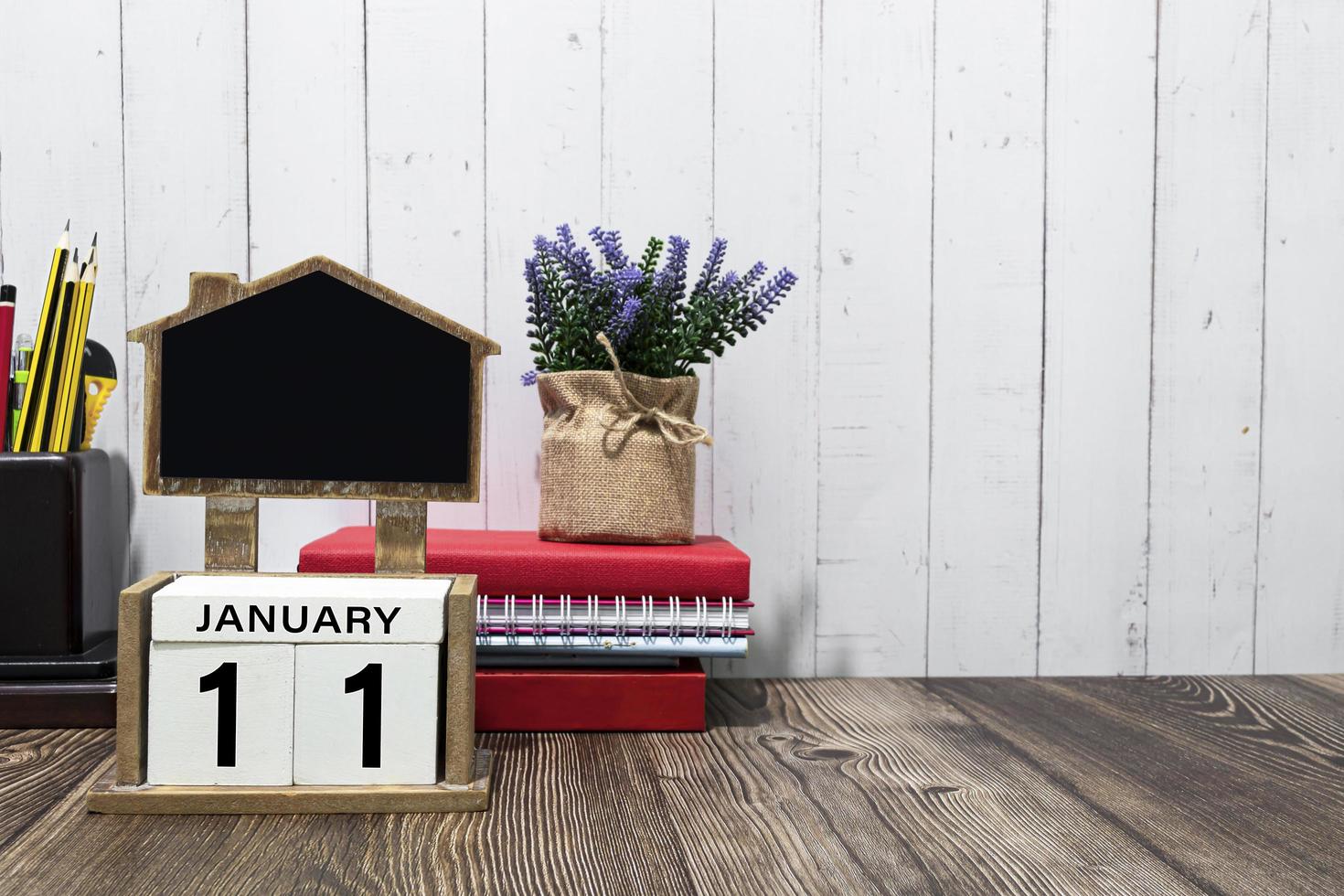 11 de enero texto de fecha de calendario en bloque de madera blanco con papelería en escritorio de madera foto