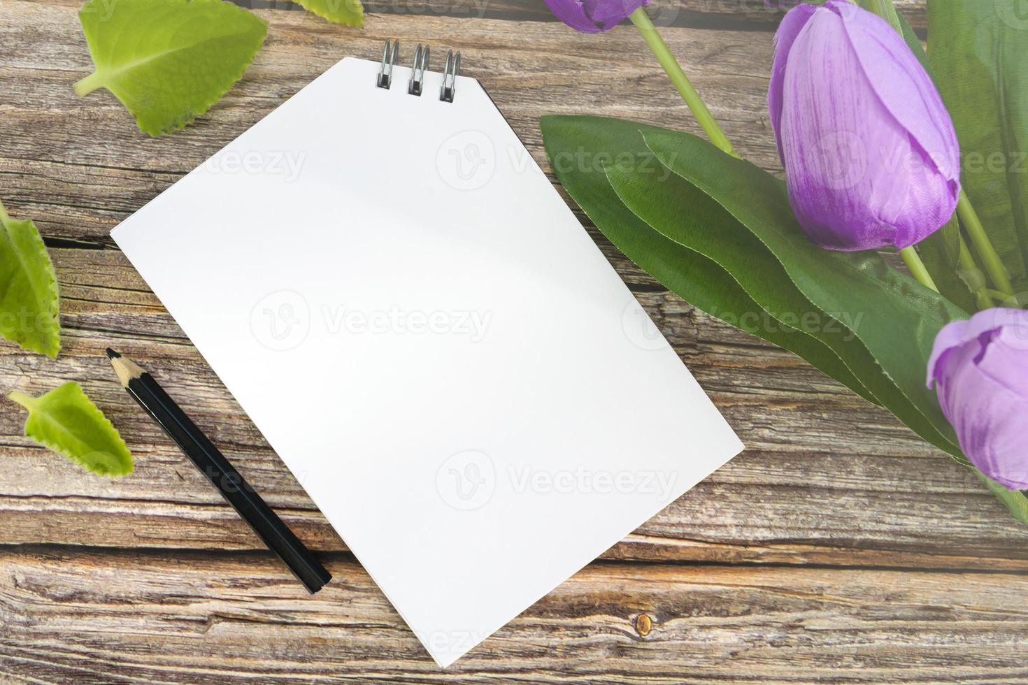 Notepad and pencil with flowers on wooden desk. Copy space. photo