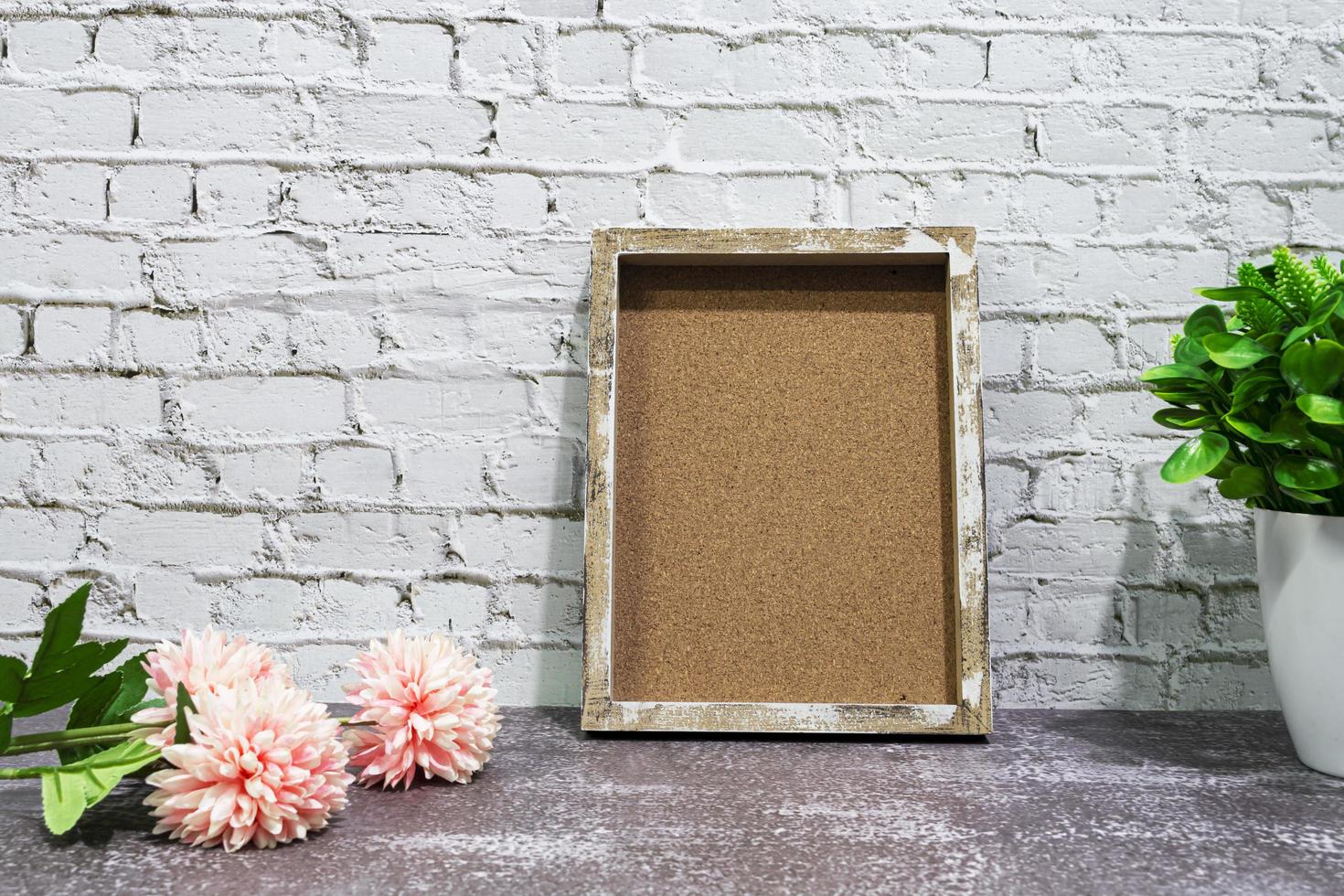 Wooden frame with potted plant and flowers on wooden background. photo