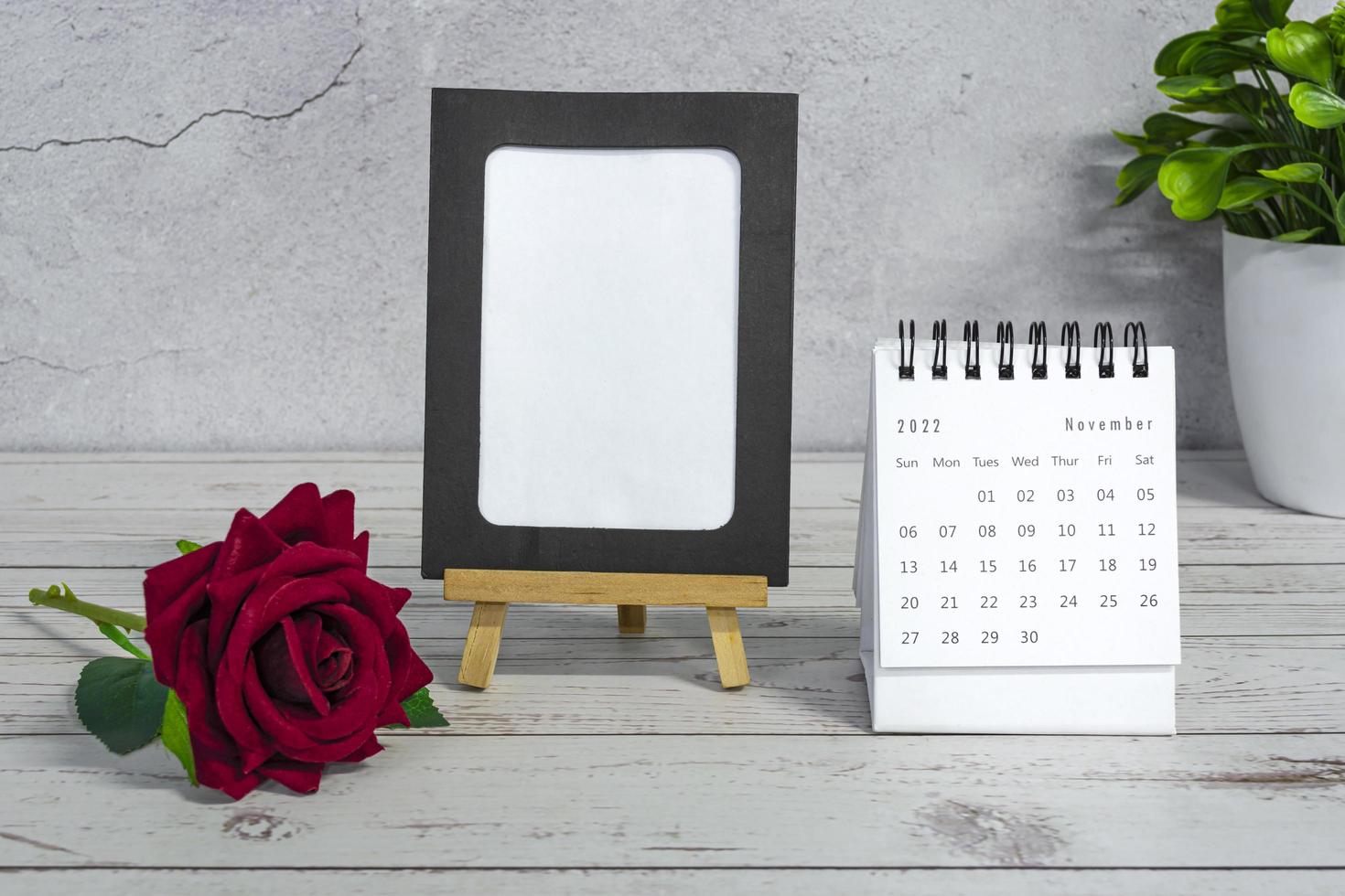 White November 2022 calendar on wooden desk with paper frame. Copy space. photo