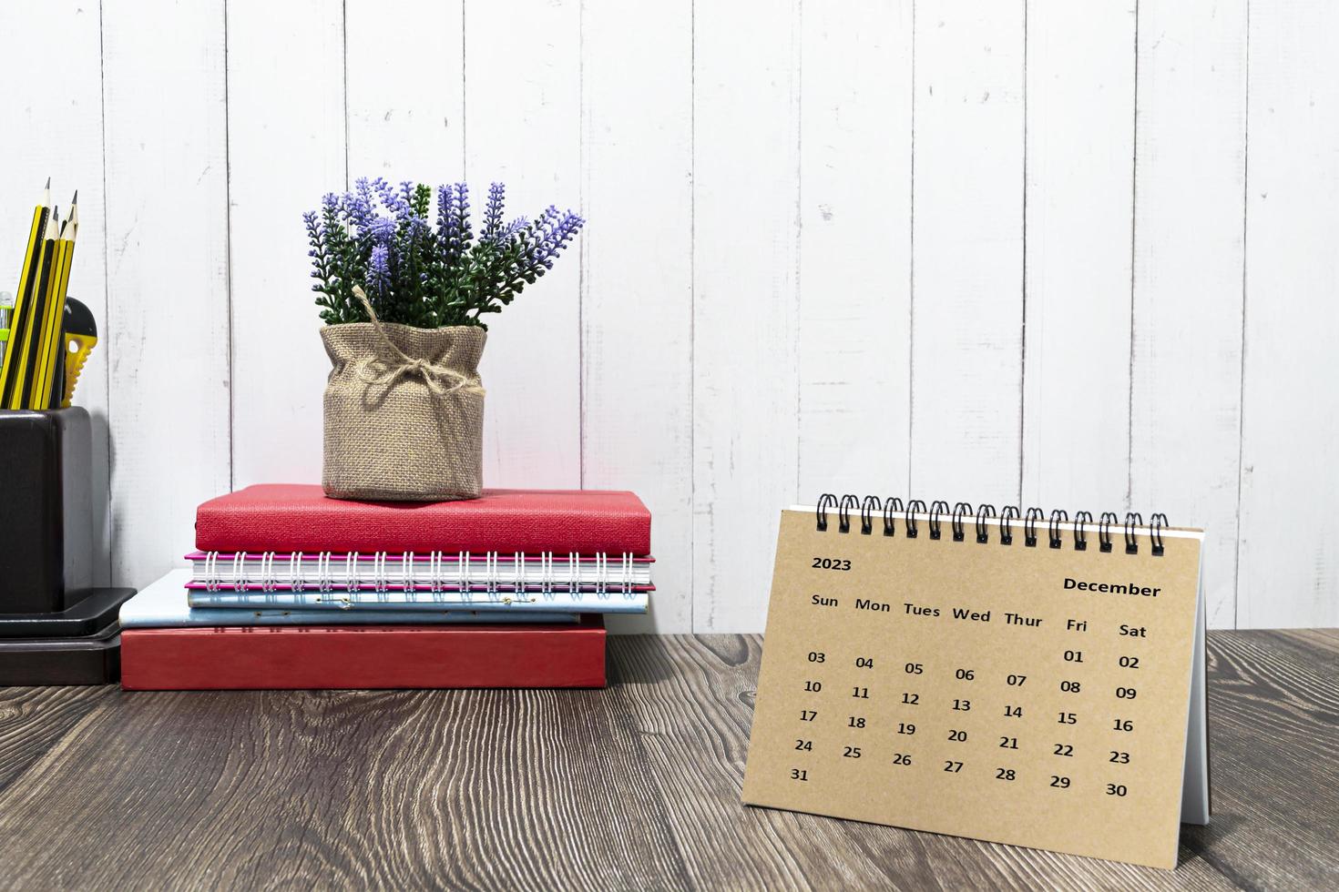 Brown December 2023 calendar on wooden desk with office stationery. photo