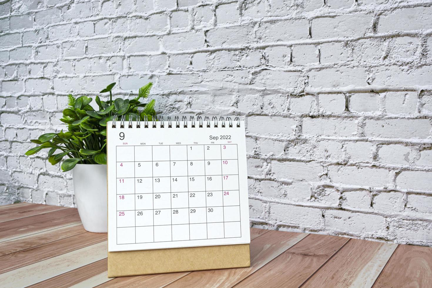 septiembre de 2022 calendario blanco con planta en maceta sobre escritorio de madera. foto