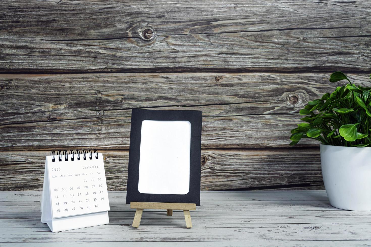 White September 2022 calendar on wooden desk with paper frame and potted plant. 2022 new year concept. Copy space. photo