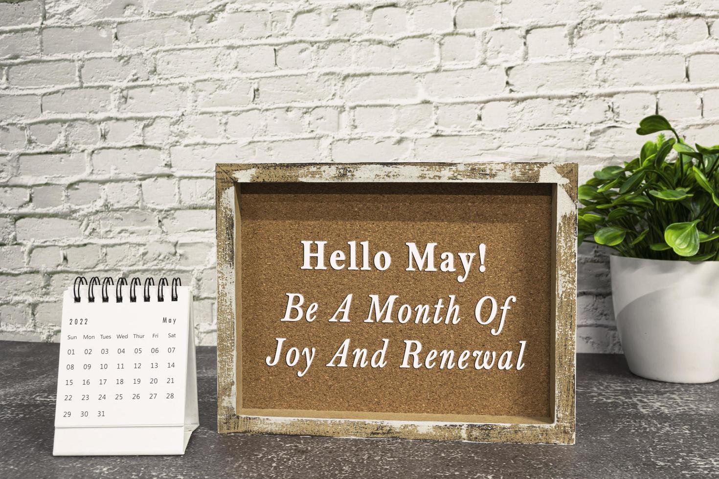 Motivational and inspirational quote on wooden frame with May 2022 calendar. photo