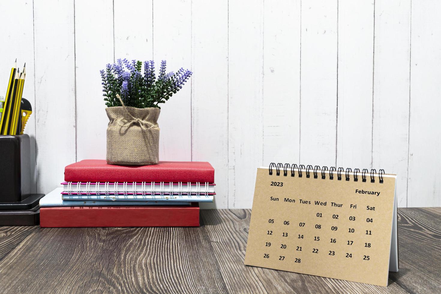 calendario marrón de febrero de 2023 en un escritorio de madera con material de oficina. foto