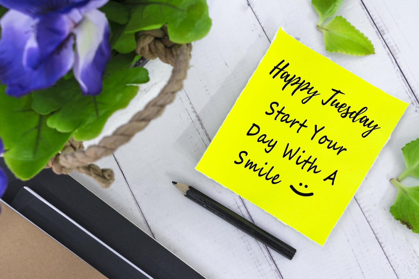 Motivational quote on yellow note with flowers on wooden background photo