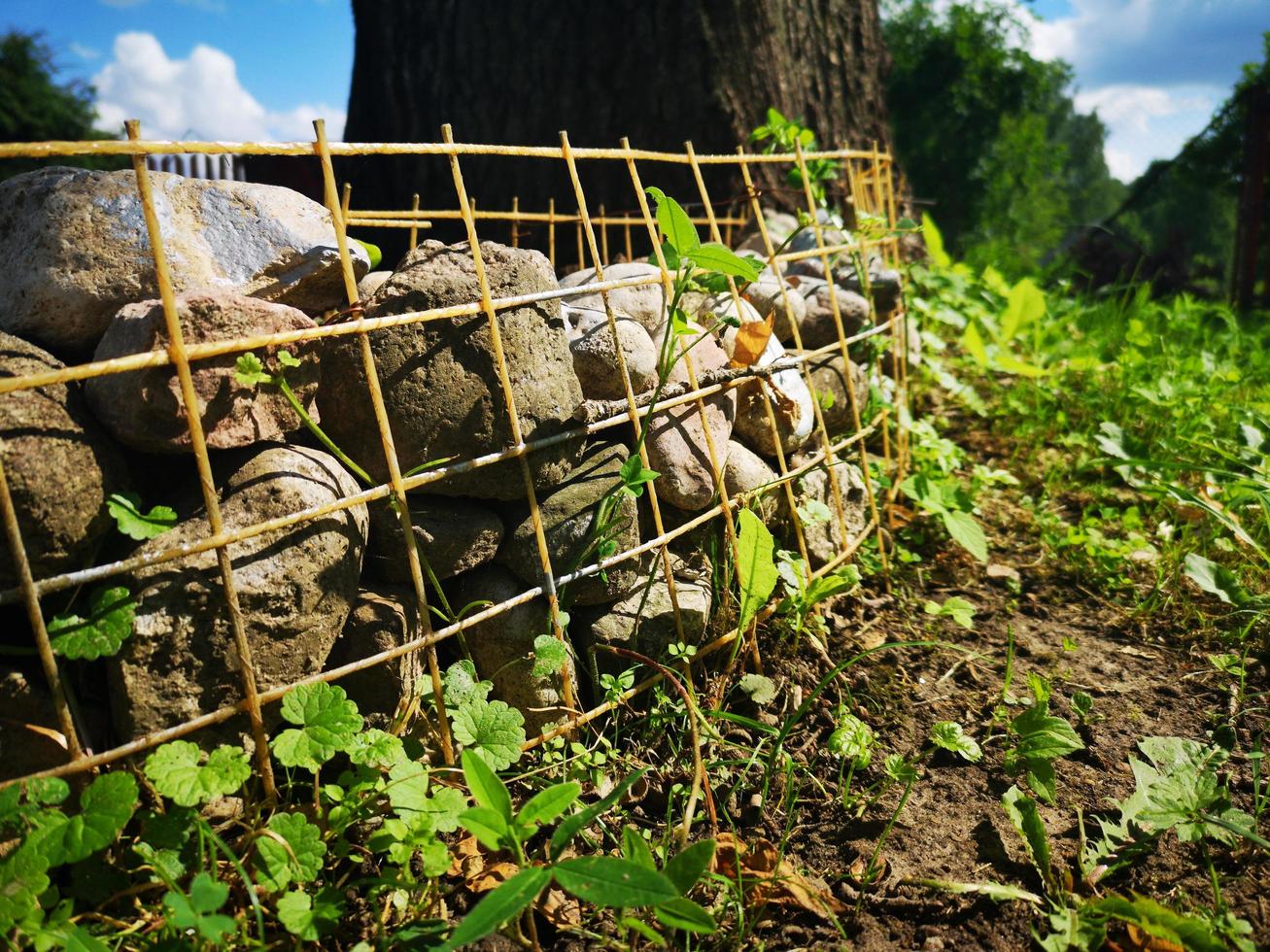 Fence at the flowerbed made of lattice and stones photo