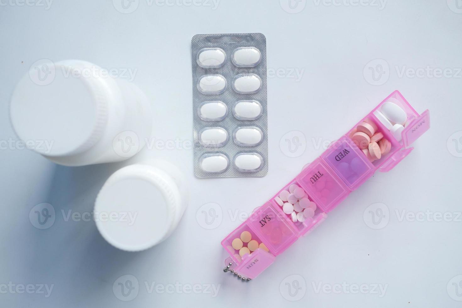 container, blister pack and medical pills in a pill box on table photo