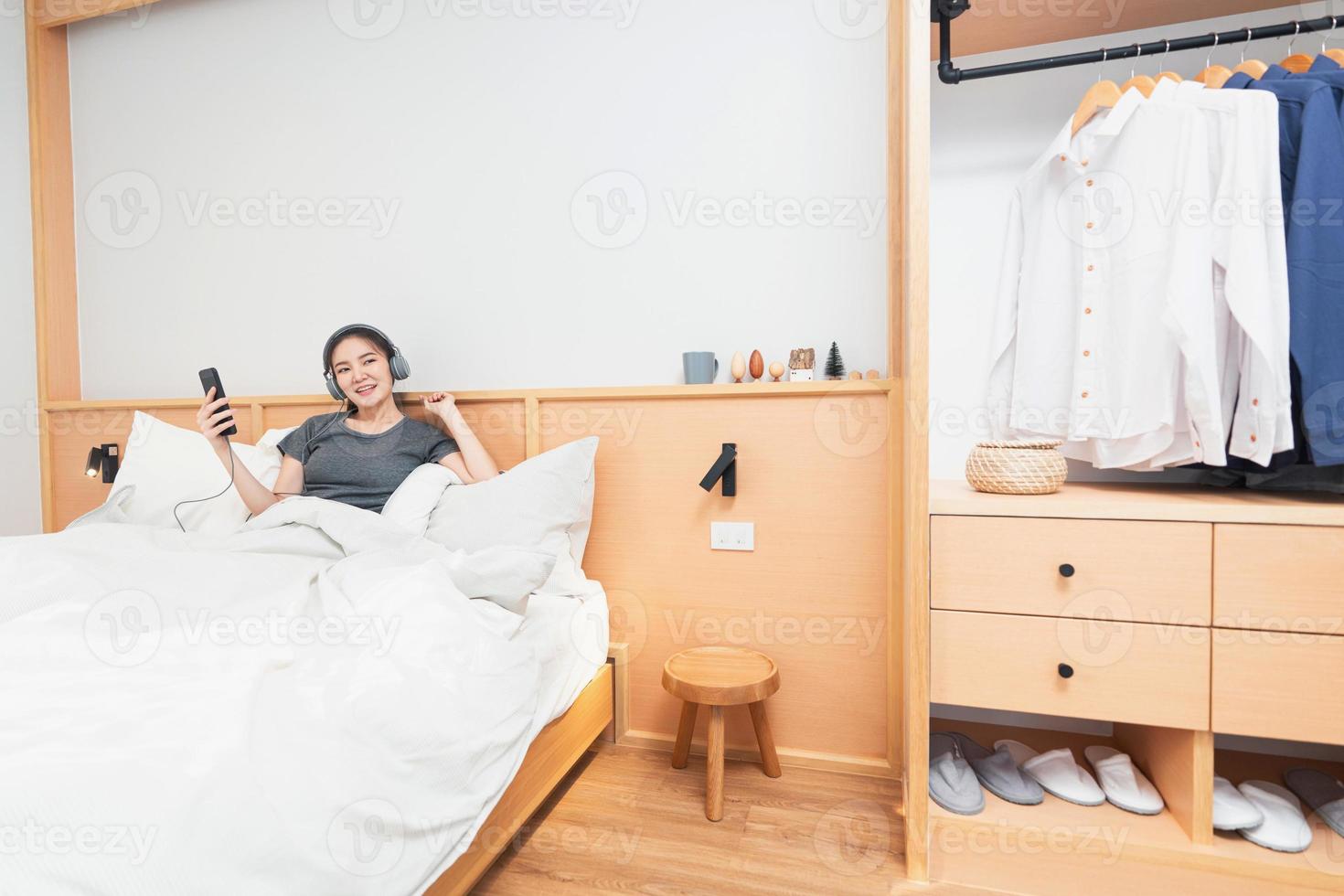 concepto de dormitorio en la cómoda cama una chica escuchando sus canciones favoritas usando un auricular por la mañana foto