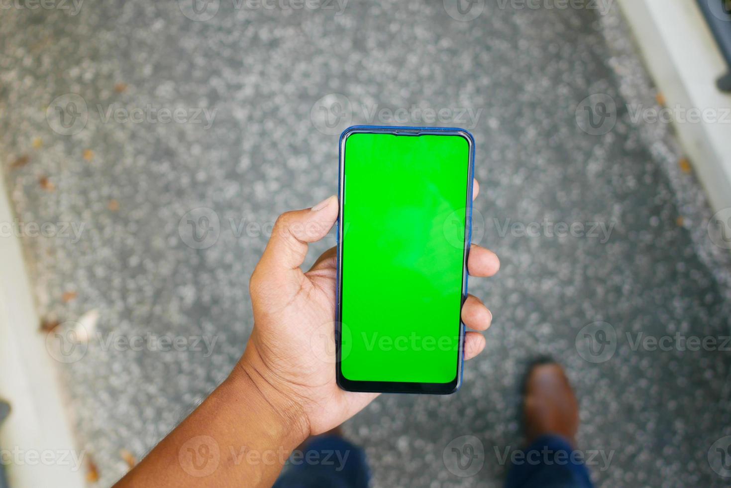 POV of young man hand using smart phone with green screen photo