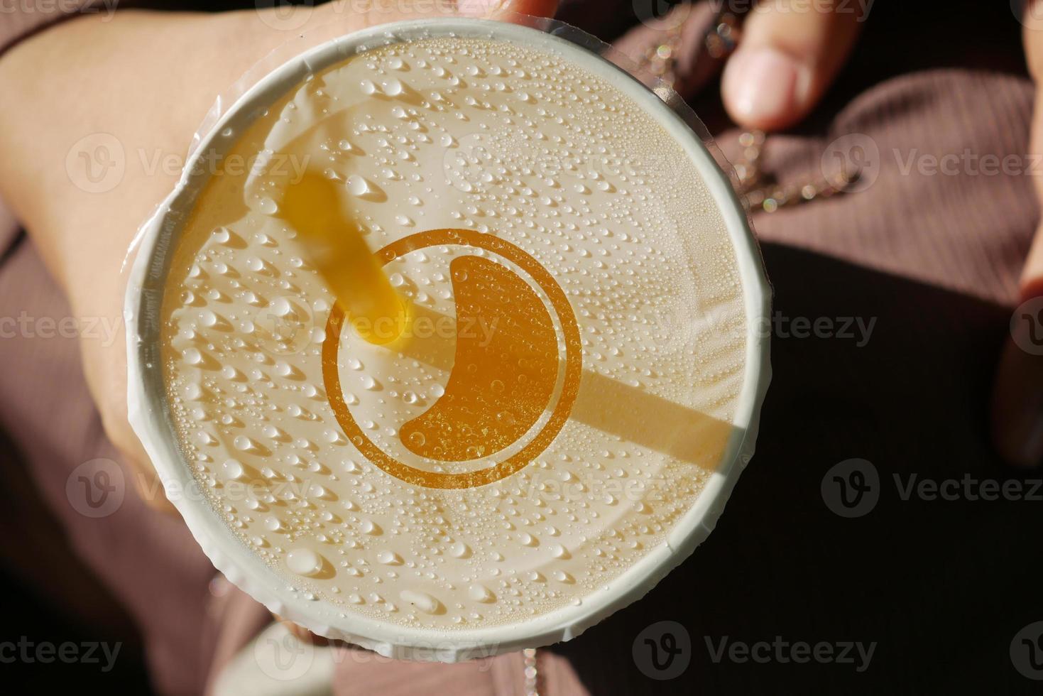 holding plastic container of orange juice close up photo