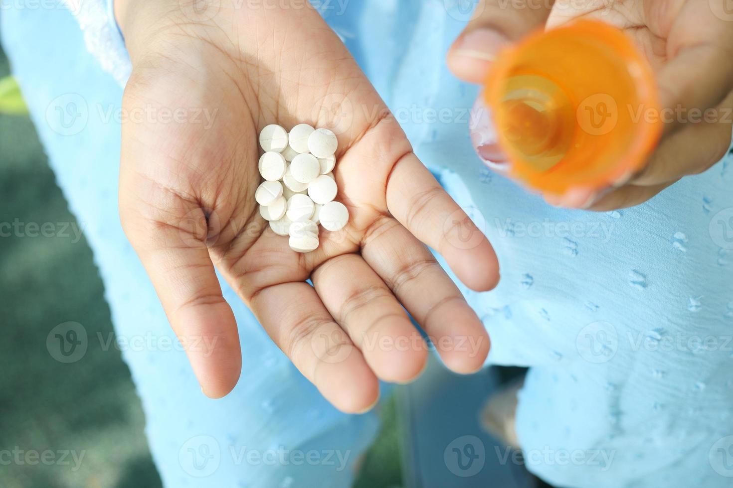 Cerca de la mano de la mujer tomando pastillas foto