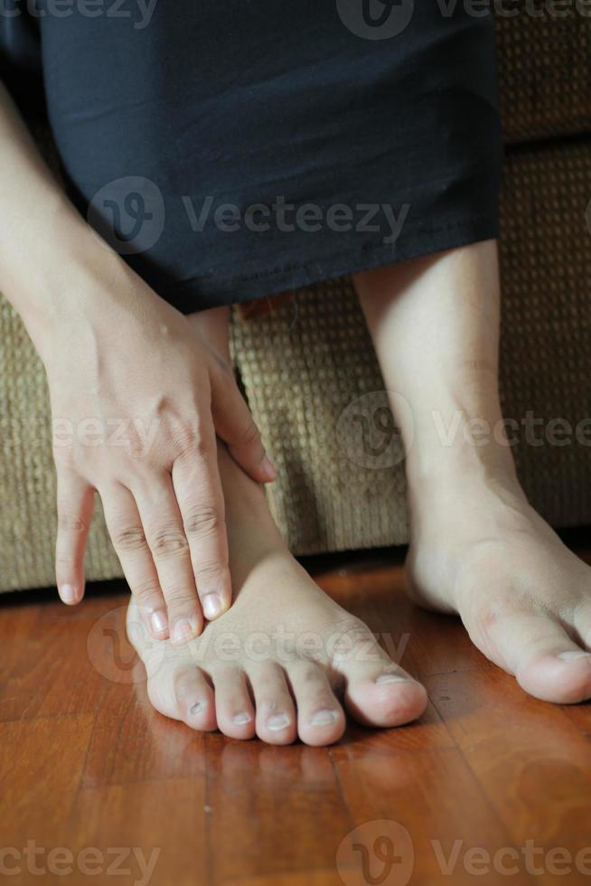 women messaging her feet sitting on sofa photo