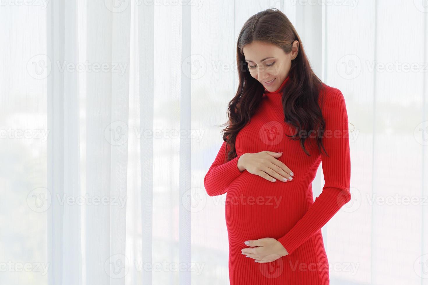A beautiful, cool, pregnant woman stood with her hands on her belly and touched the unborn child tenderly, cherishly and happily with a smiling face photo