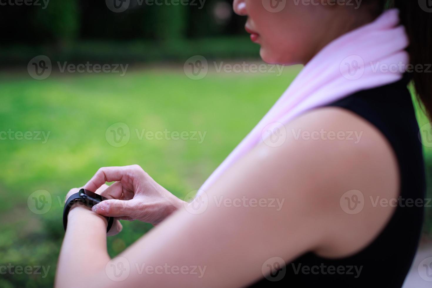 las mujeres deportivas irreconocibles con ropa deportiva levantan la mano y usan el dedo para ajustar la aplicación de configuración en el reloj inteligente en la muñeca para verificar el resultado después del entrenamiento o ejercicio. concepto de buena atención médica foto