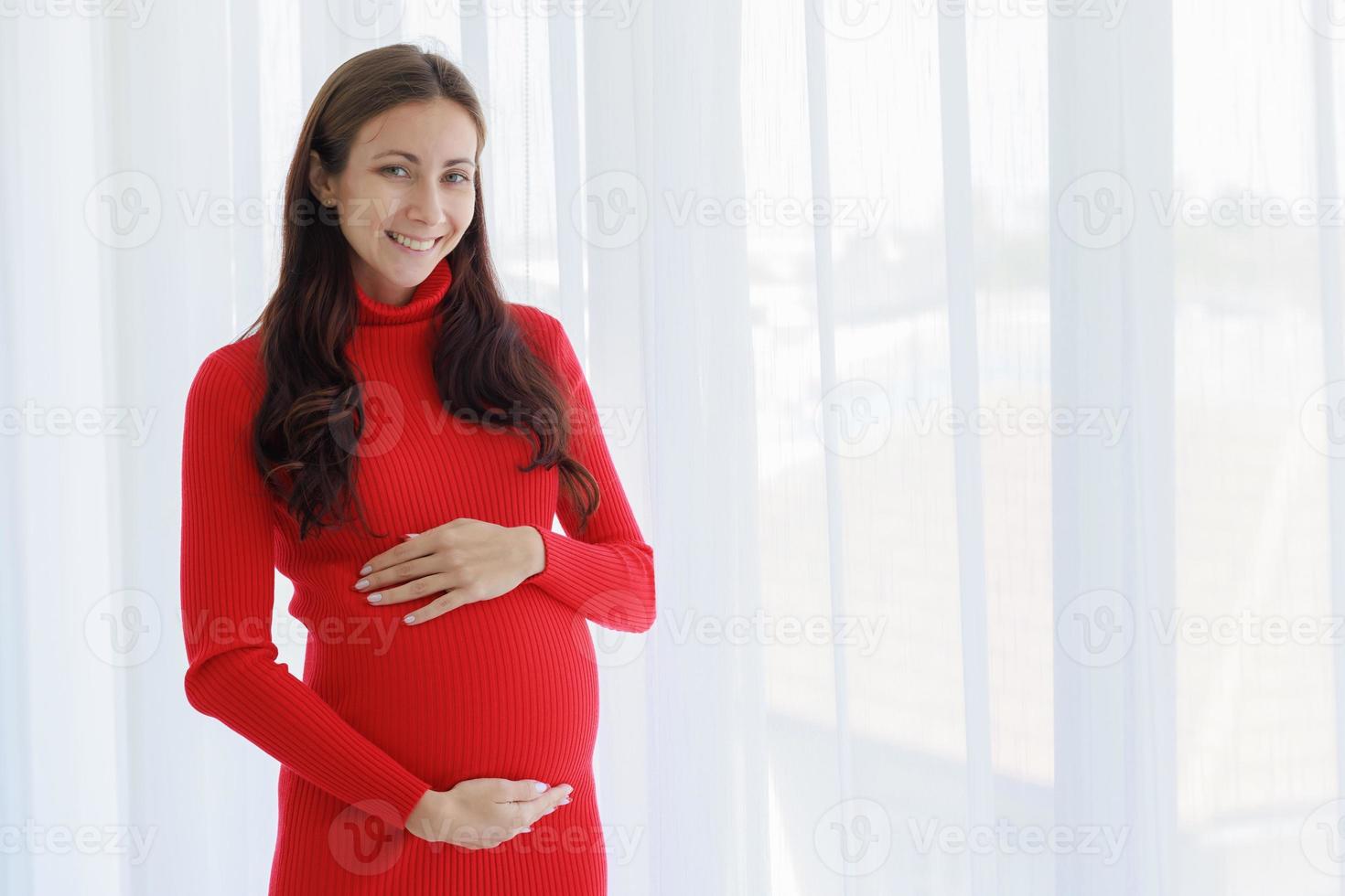 A beautiful, cool, pregnant woman stood with her hands on her belly and touched the unborn child tenderly, cherishly and happily with a smiling face photo
