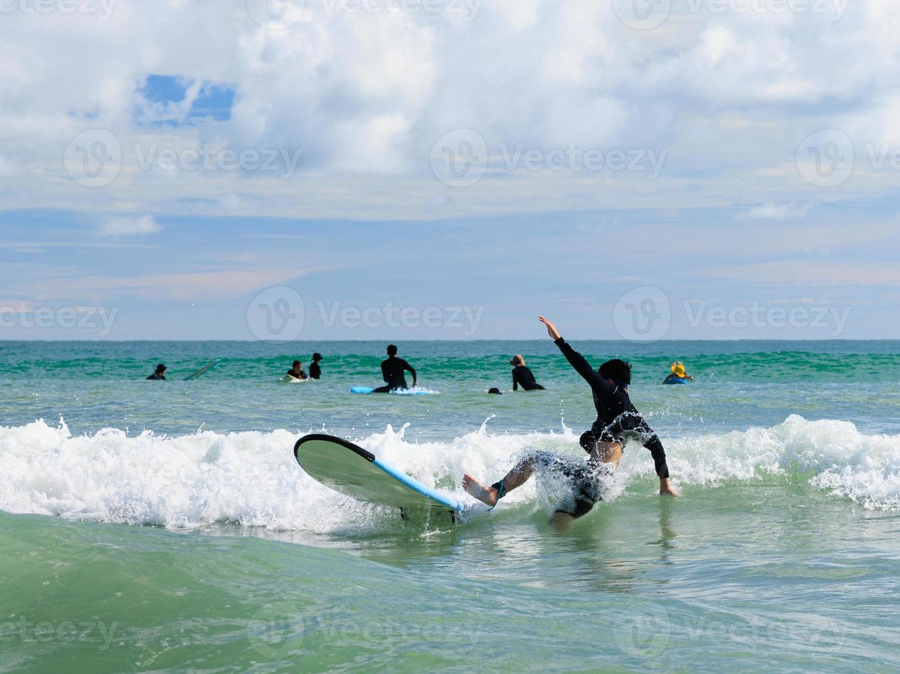 A young boy, a new student in surfing, loses his grip and falls from a surfboard into the water during class. photo