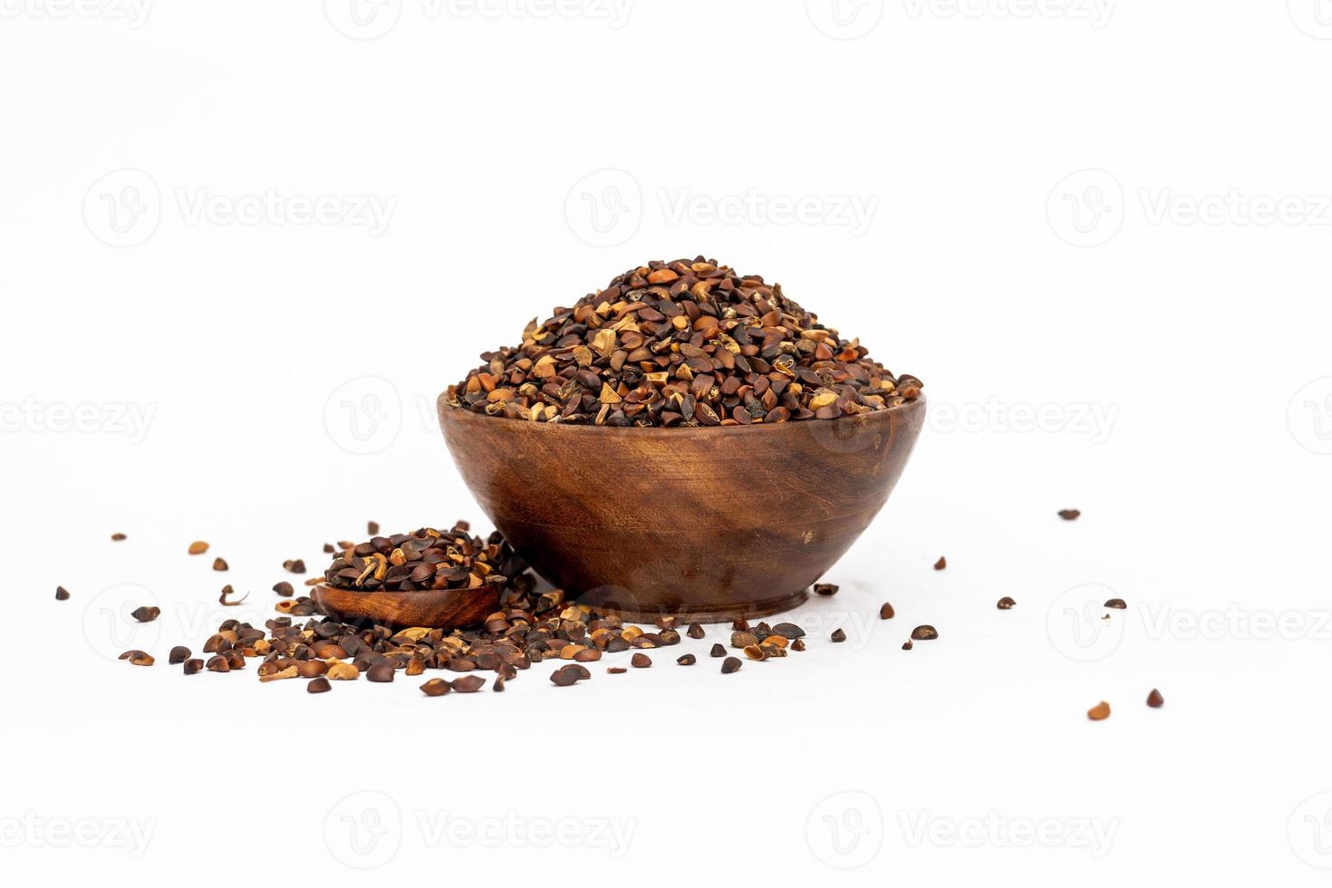 Indigofera or indigo seeds in wooden bowl isolated on white background photo