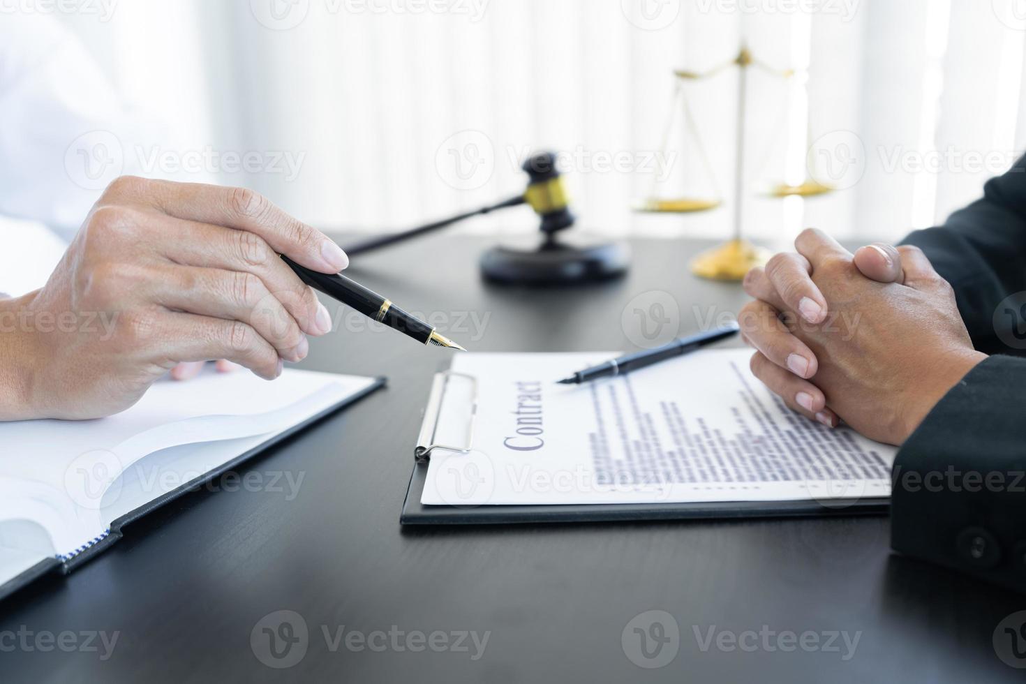 law,libra scale and hammer on the table, 2 lawyers are discussing about contract paper, law matters determination photo