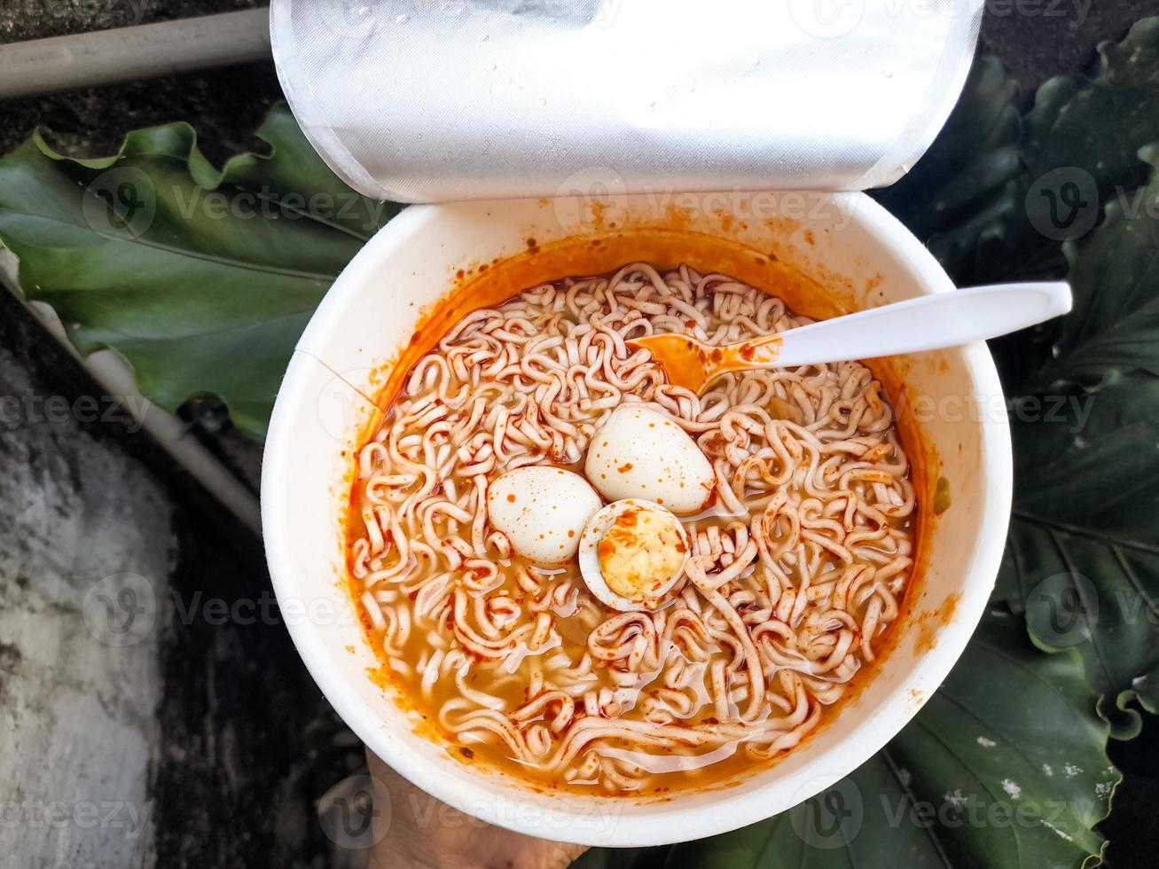 Taza picante de fideos instantáneos con aderezos adicionales de huevos de codorniz cocidos, muy deliciosos y sabrosos. foto