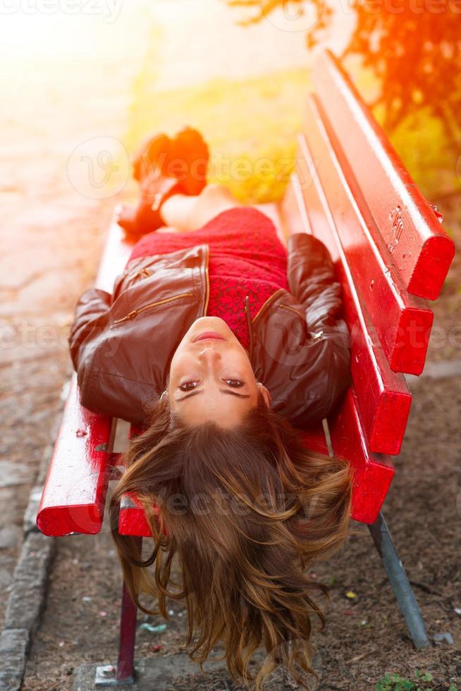 ng chica acostada en un banco rojo con el pelo largo hacia atrás foto