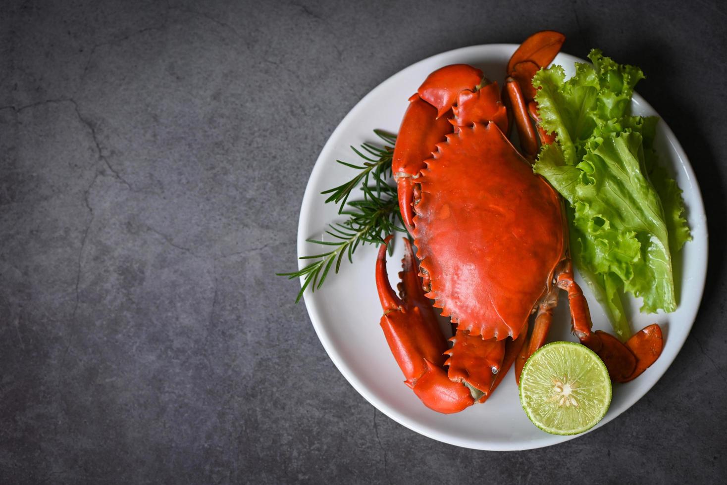 seafood crab cooking food boiled or steamed crab red in the seafood restaurant, fresh crab on white plate dark background - top view photo