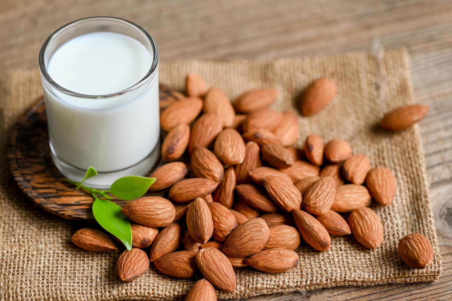 Almond milk and Almonds nuts on on sack background, Delicious sweet almonds on the table, roasted almond nut for healthy food and snack photo