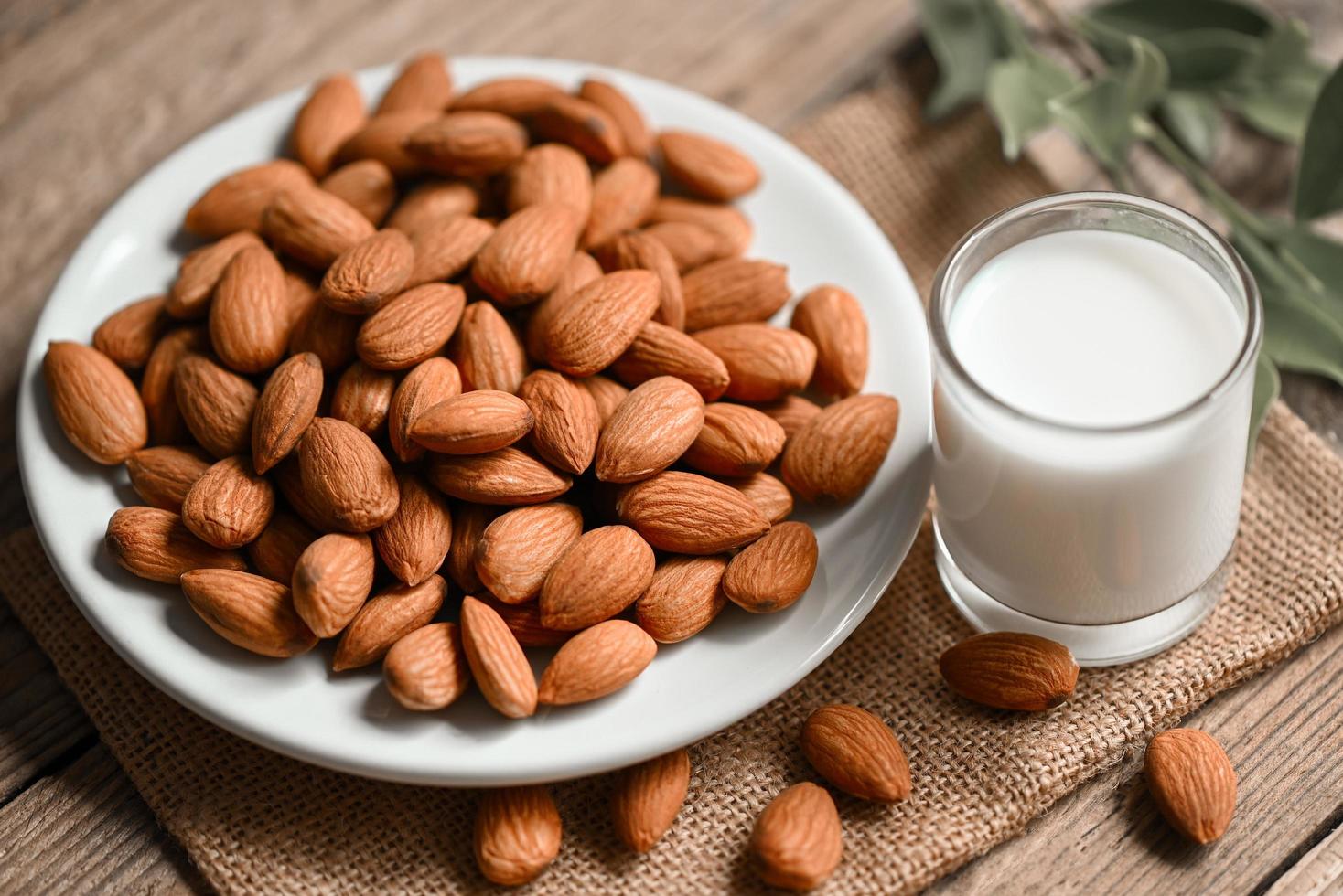 Almond milk and Almonds nuts on on white plate background, Delicious sweet almonds on the table, roasted almond nut for healthy food and snack photo