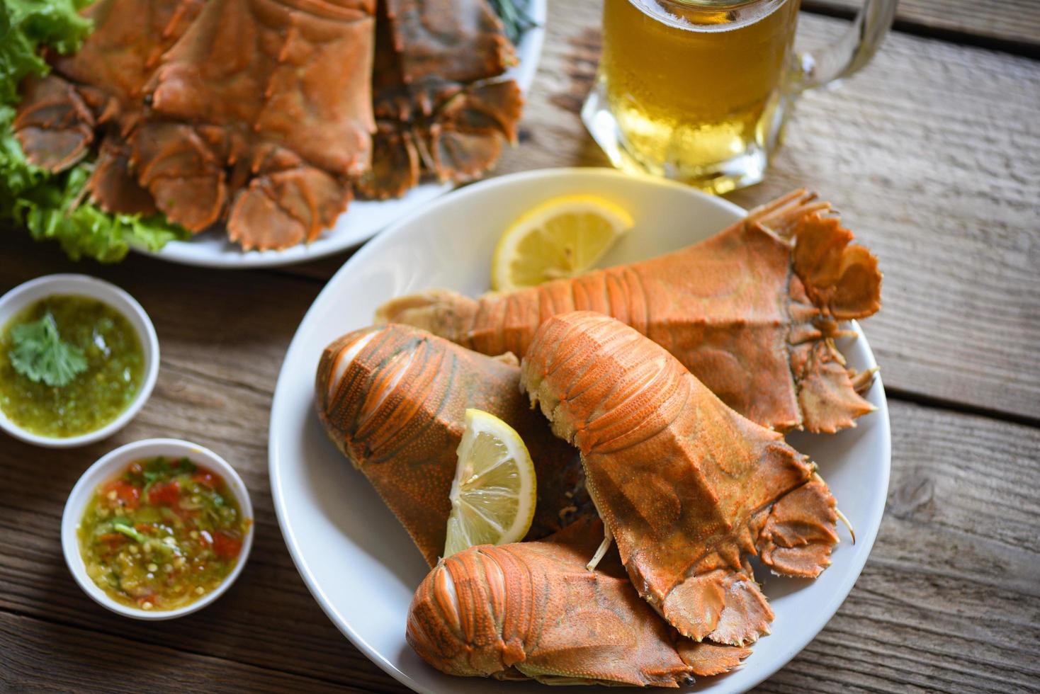 Fresh slipper lobster flathead boiled cooking with parsley rosemary in the restaurant, Flathead lobster shrimps served on white plate seafood sauce and mug beer glass, Rock Lobster Moreton Bay Bug photo