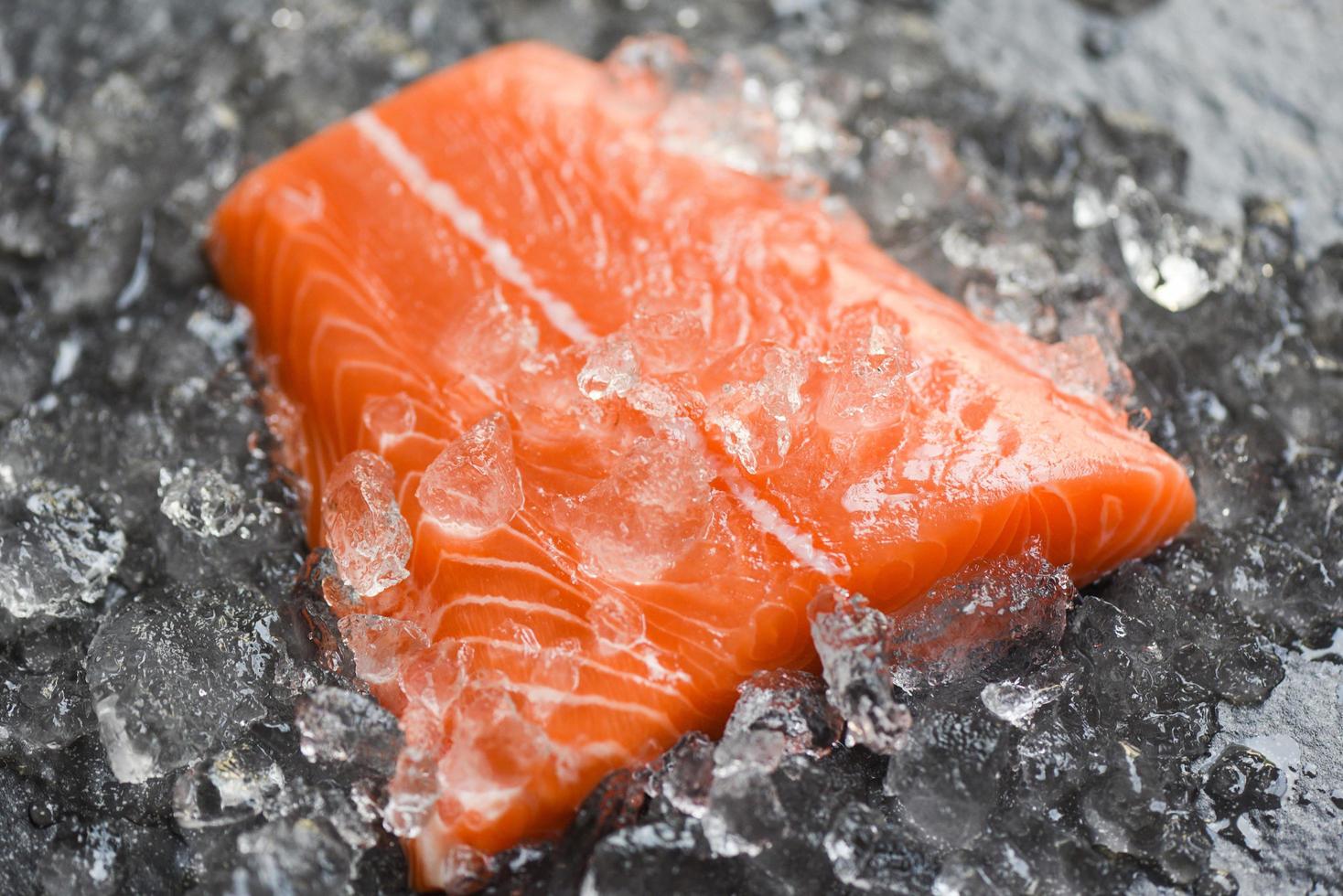 Fresh raw salmon fish steak on ice and dark stone background photo