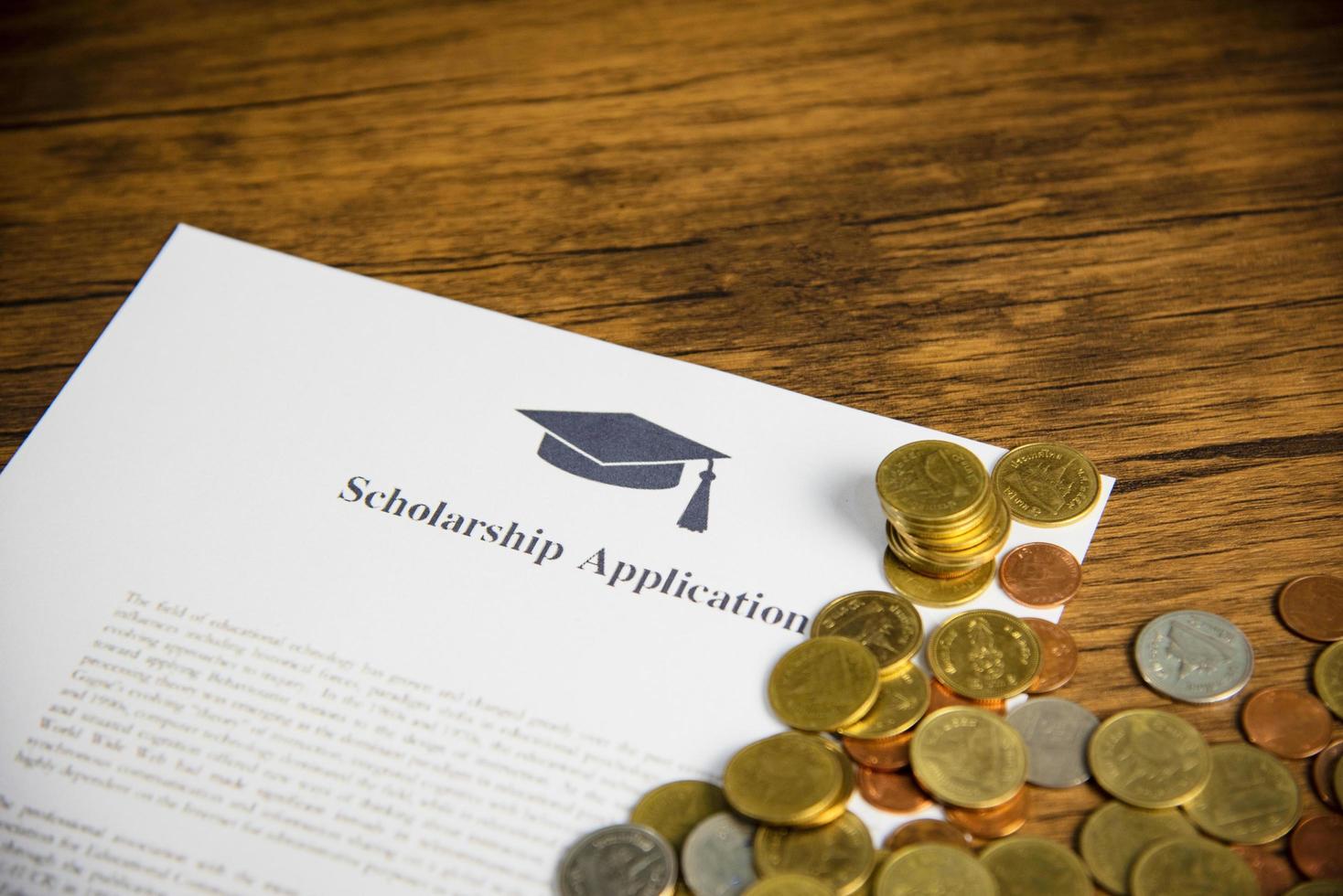 Scholarship application document contract form concept with money coin for grants scholarships education on wooden table photo
