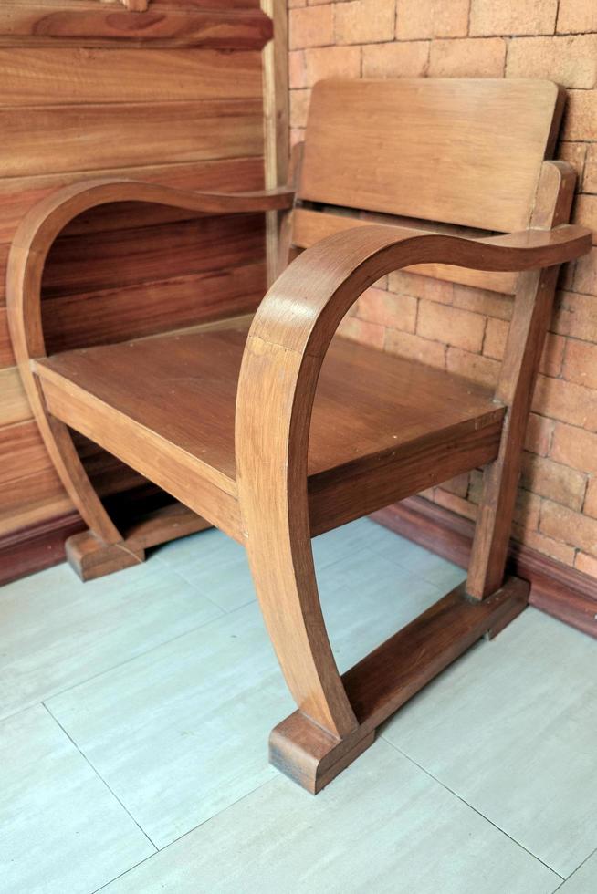 A vintage wooden chair placed in a corner of a room with brick and wood walls. photo