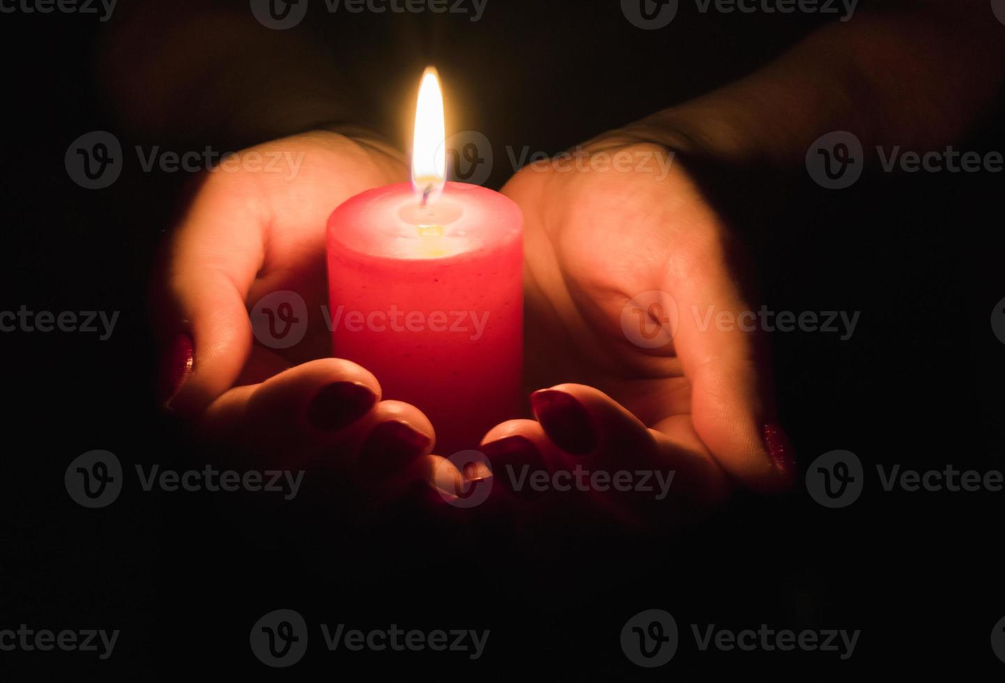 manos femeninas sosteniendo una vela encendida en la oscuridad foto