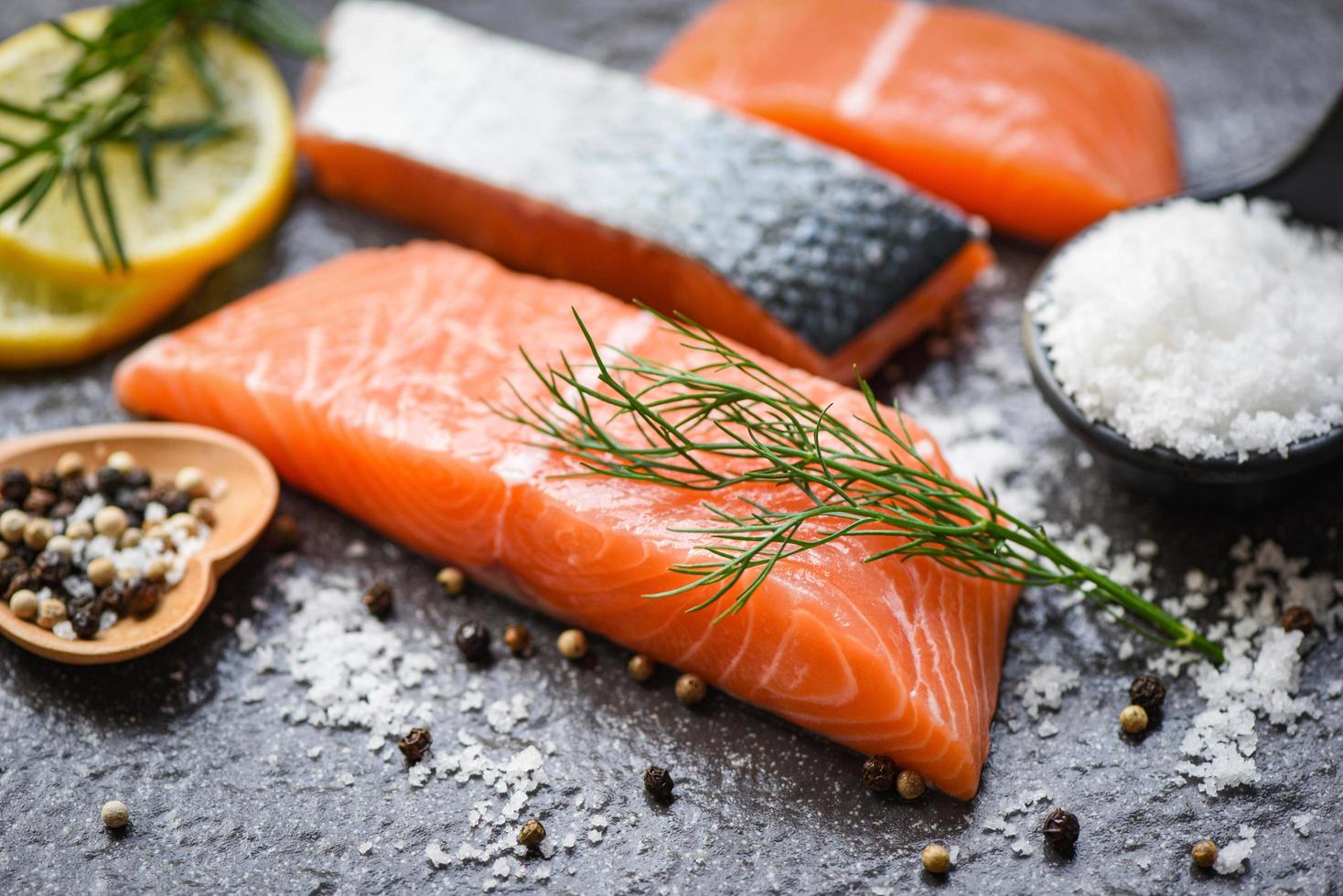 Raw salmon filet with herbs and spices on dark black background photo