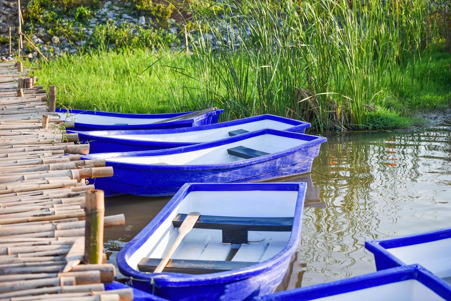 Plastic boat on the riverside lake and wooden bridge photo