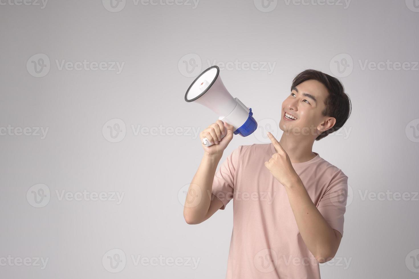 Young smiling man holding megaphone over white background studio. photo
