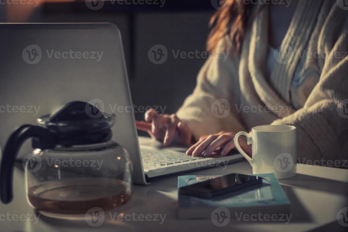 Unrecognizable woman is using laptop late in the evening. photo