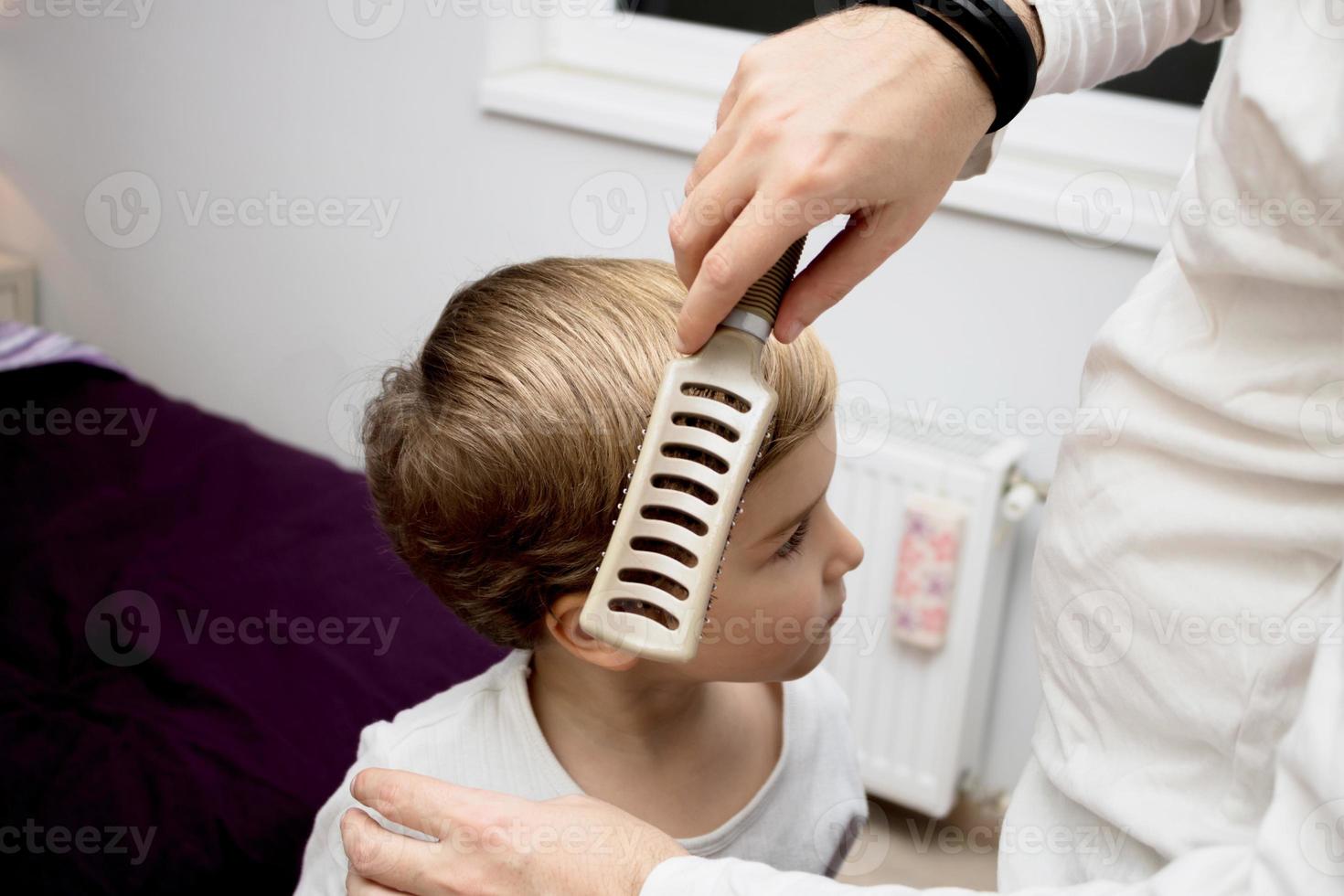 Close-up of father brushing son's hair. photo