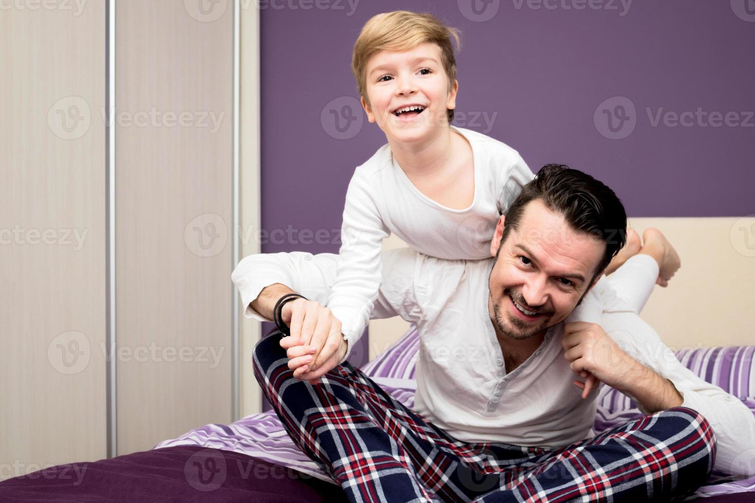 Happy father and son having fun while playing on the bed. photo