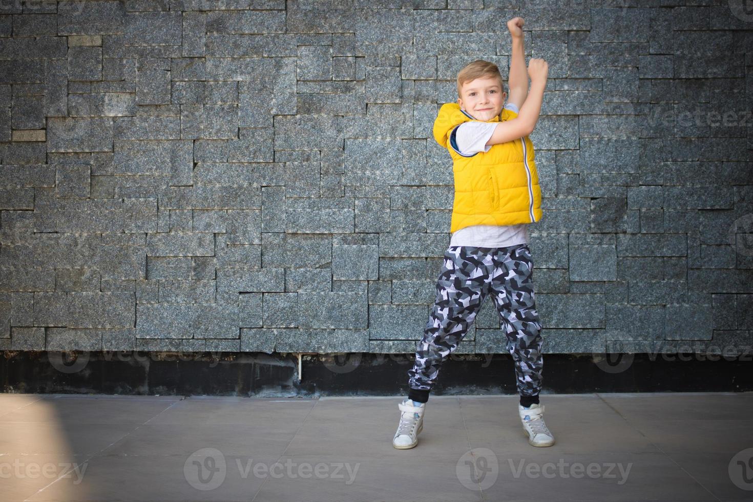 Playful kid dancing against the wall. photo