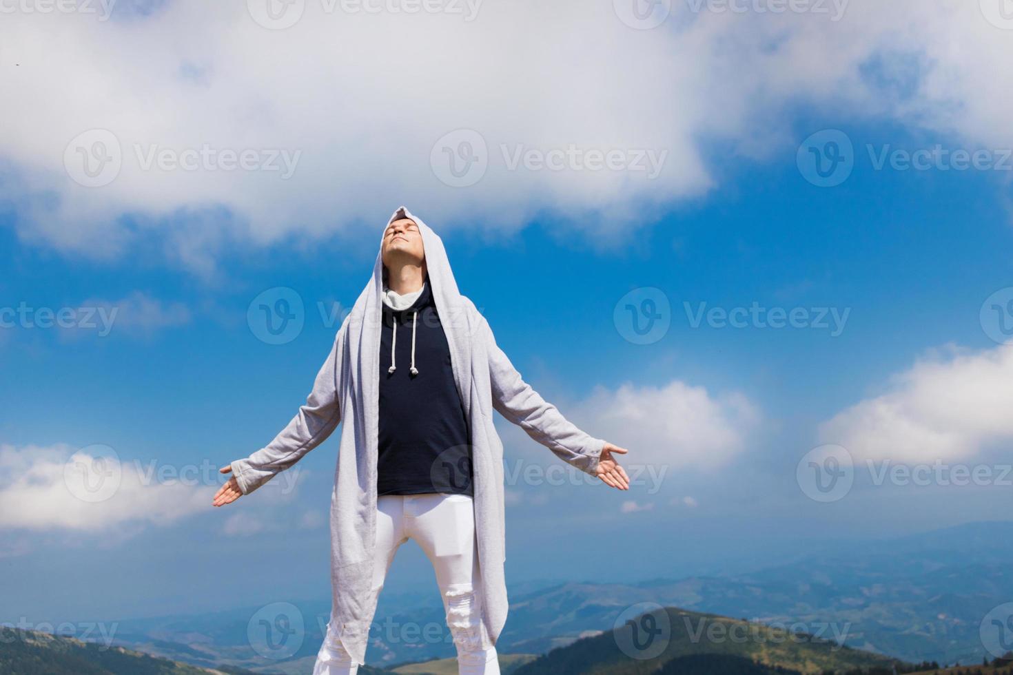Carefree man standing on top of the mountain with arms outstretched. photo
