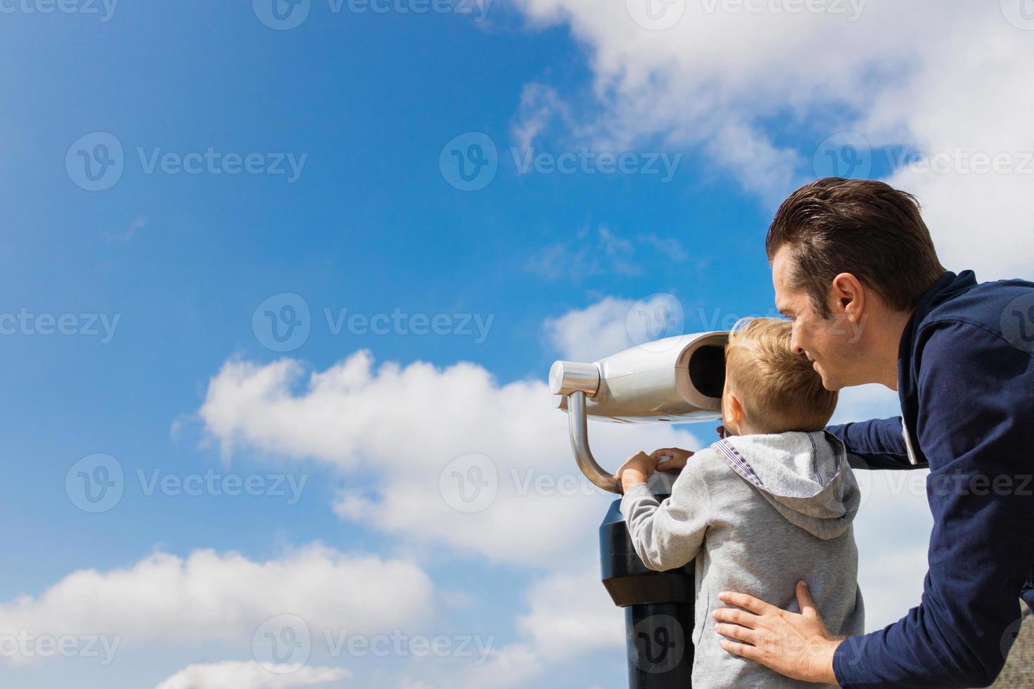 padre e hijo mirando a través de binoculares contra el cielo. foto