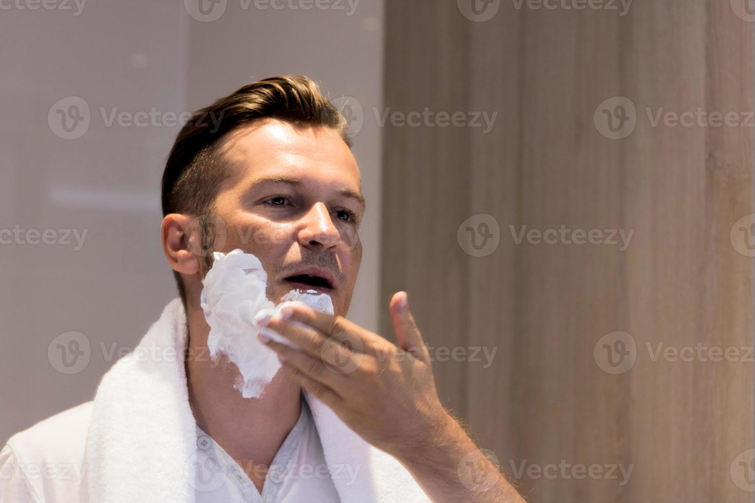 Man applying shaving foam on face in the morning. photo