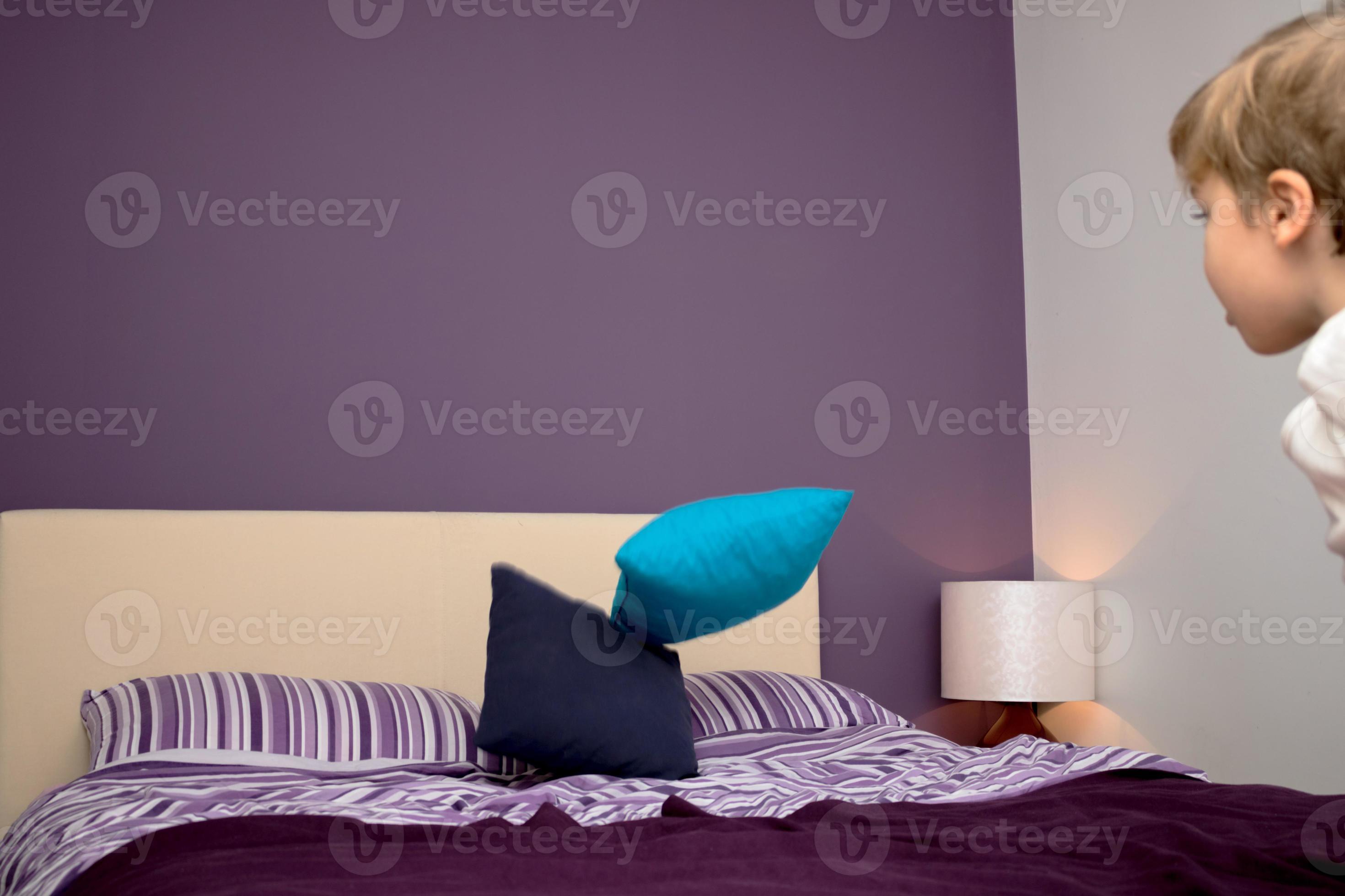 Playful boy throwing pillows on the bed. 11217058 Stock Photo at Vecteezy