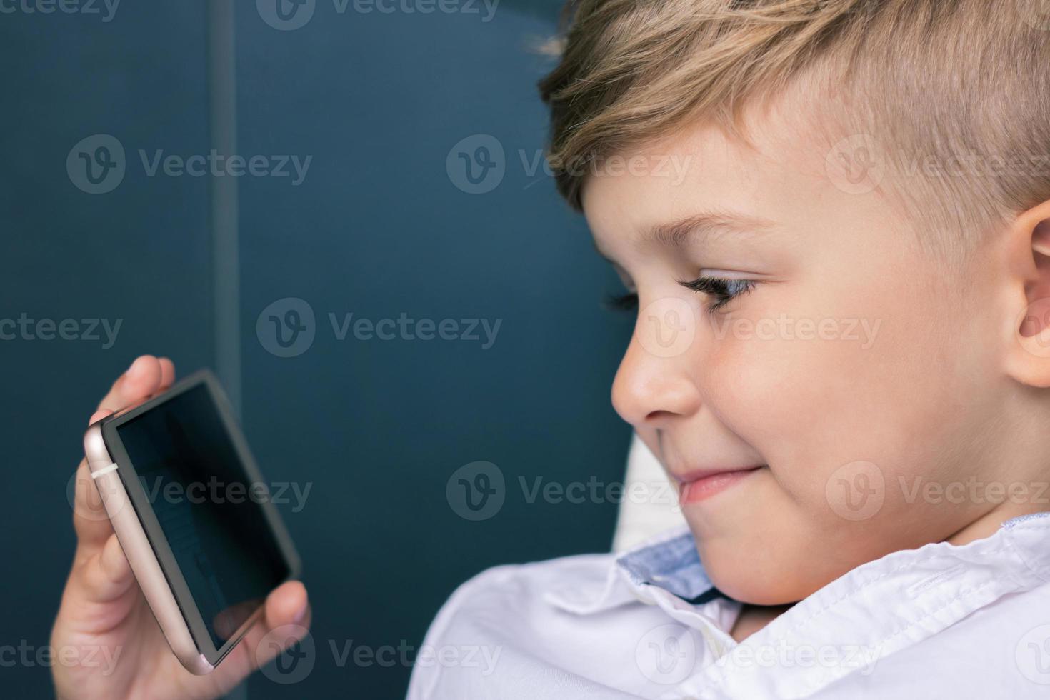 niño sonriente viendo dibujos animados en línea en el teléfono inteligente. foto