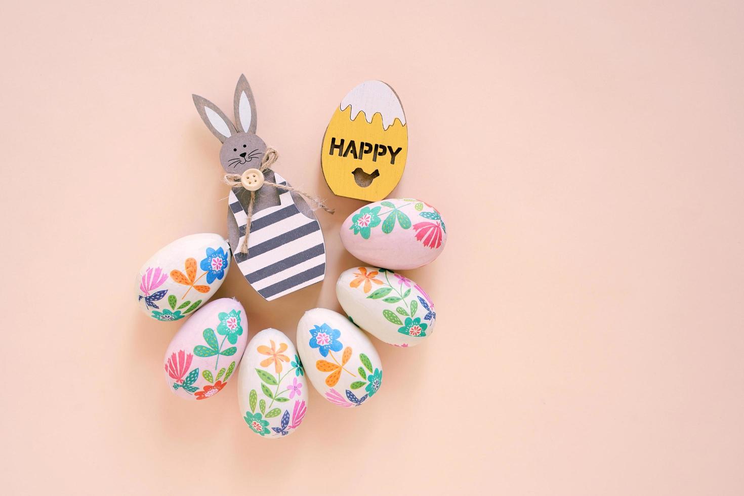 Happy Easter concept with wooden bunny and colorful easter eggs on yellow background. Top view with copy space photo